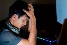 stressed-young-man-in-front-of-computer-in-dimly