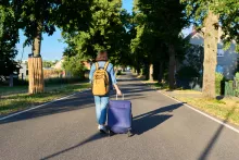 woman with suitcase walking down road
