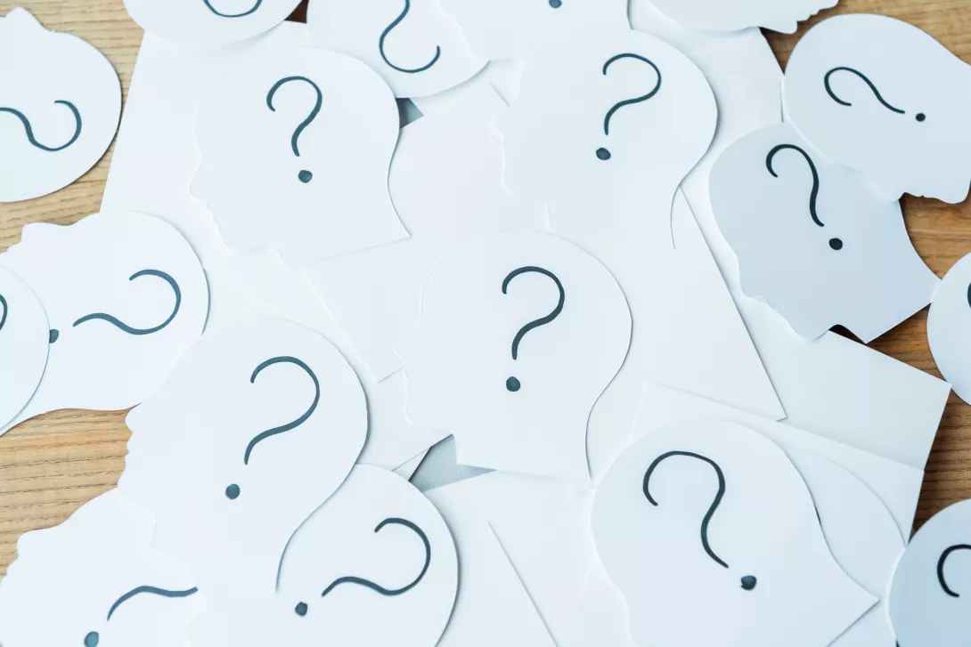 question-marks-on-paper-with-human-heads-on-wooden