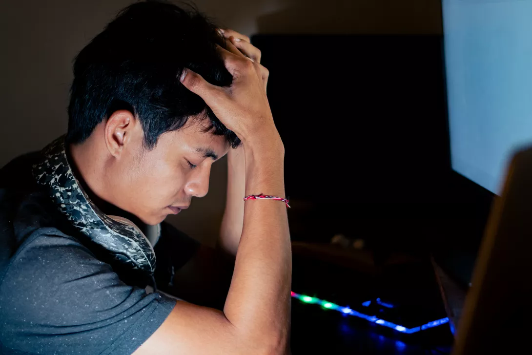 stressed-young-man-in-front-of-computer-in-dimly