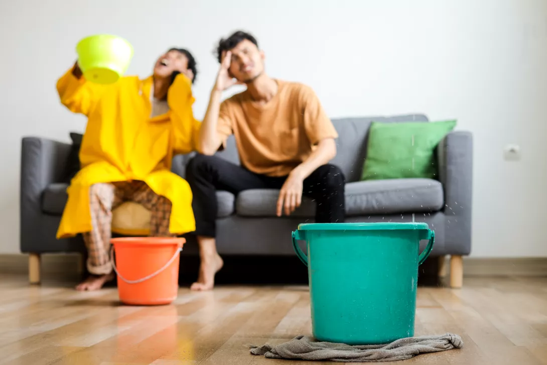 two-people-holding-pot-under-leaking-ceiling