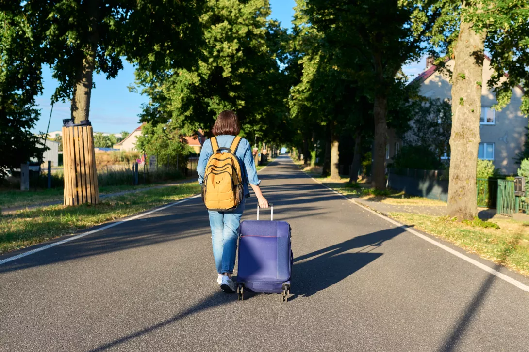woman with suitcase walking down road