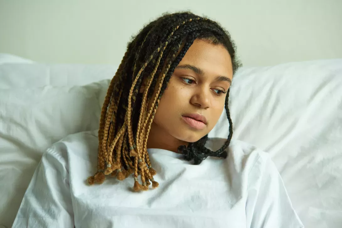 Young person in hospitable bed looking sad